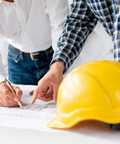 Due ingegneri esaminano i progetti, con il casco nelle vicinanze. EDIL LUC SERVIZI DI RISTRUTTURAZIONE ROMA Due ingegneri esaminano i progetti, con il casco nelle vicinanze. EDIL LUC SERVIZI DI RISTRUTTURAZIONE ROMA